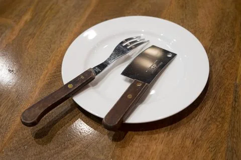 Fork and knife are put on a white plate. Stock-Fotos