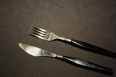 Fork and knife. Black kitchen utensils placed on a black table. Top view Stock Photos