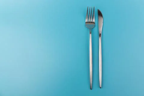 A fork and knife on blue background. Flat lay Dishes for breakfast, lunch or  Stock-Fotos