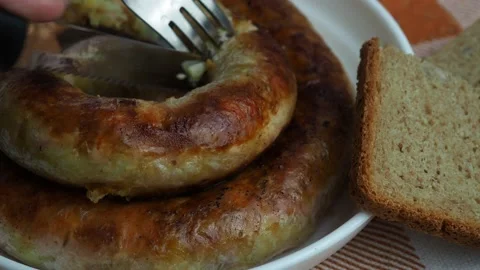 With a fork and knife, a piece is cut off, from the diet sausage Stock Footage 130494424