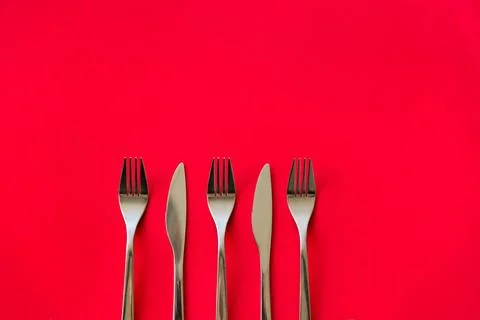 Fork and knife on a red background. Flat lay, top view. Stock Photos