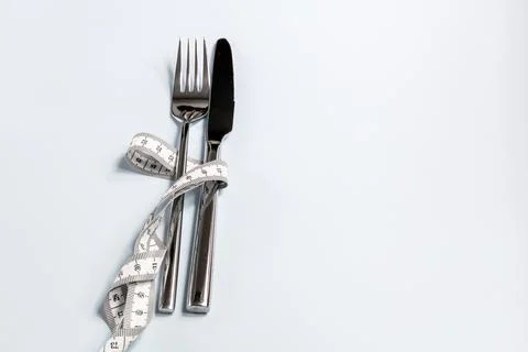 Fork and knife wrapped in a measuring tape Stock Photos