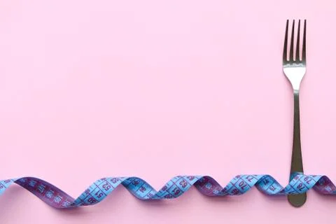 Fork and meter on a pink background, concept of weight loss, space for text Stock Photos