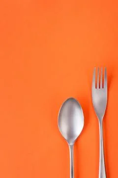 Fork and spoon on orange background, sparse composition with copy space Foto stock