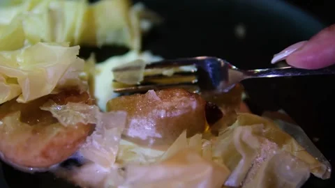 Fork breaking caramelized pear with crispy puff pastry and creamy syrup on black Stock Footage 318296635