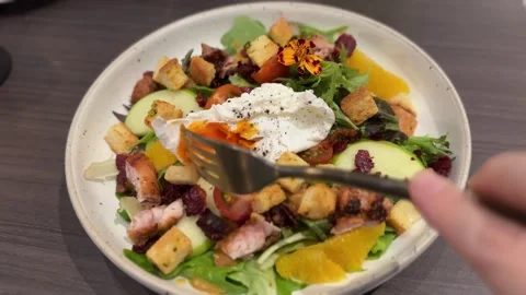 Fork Breaking Runny Poached Egg on Fresh Mixed Salad, 4K Stock Footage 345647049