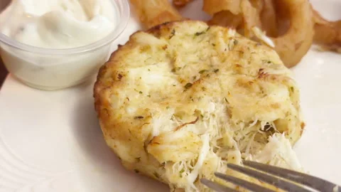 Fork breaks open Maryland Crab Cake with tartar sauce and onion rings. Stock-Footage 344906168