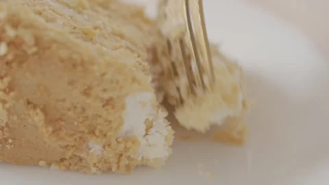 Fork breaks off piece of honey cake, showing cream filling and crumbs Video stock 341980973