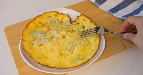 Fork cutting omelette on plate over wooden board, breakfast waiting, crispy Stock Footage 315692347