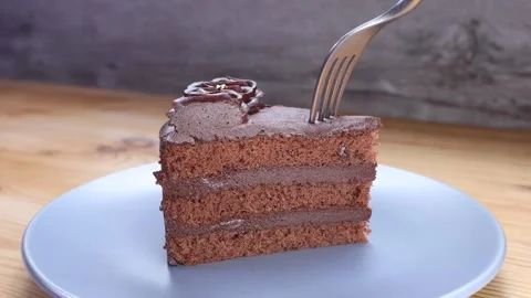 Fork cutting through a delicious slice of rich layered dark chocolate cake Stock Footage 346717361
