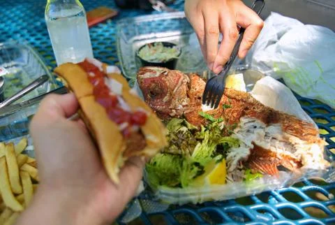 Fork digging in to a crunchy fried red snapper fish on a beautiful summer day Stock Photos