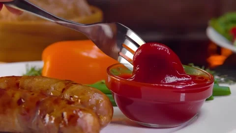 A fork dips a piece of delicious fried sausage into ketchup Stock Footage 292678862