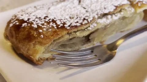 Fork on a dish near a slice of apple strudel covered with powdered sugar Video stock 299609123