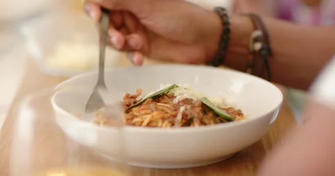Fork entering frame is puncturing spaghetti in bowl on table, twisting strands Stock Footage 340393153