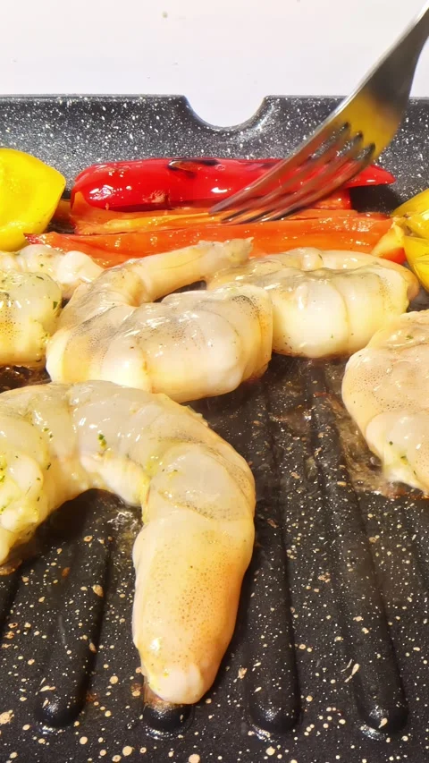 Fork Flipping Red and Yellow Peppers on Ridged Grill Pan With Peeled Shrimp Stock Footage 339078501
