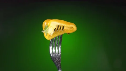 Fork with fresh yellow chopped pepper, rotation green background Stock Footage 86614731
