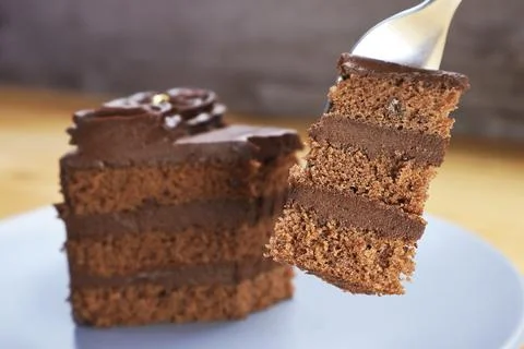 Fork lifting a delicious slice of rich layered dark chocolate cake Stock Photos