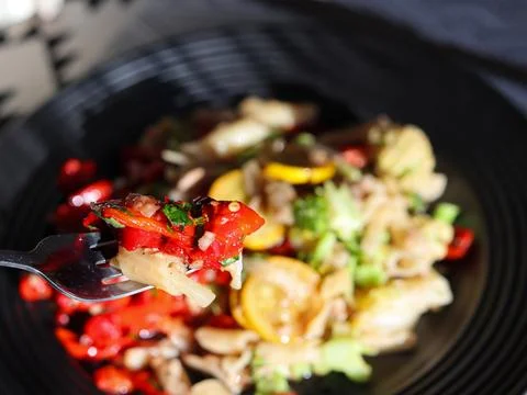 Fork lifting a serving of vegetables from a black bowl at a meal Foto stock