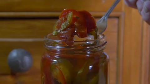 Fork lifting sliced red and green jalapeno peppers from a jar. Stock Footage 164054749