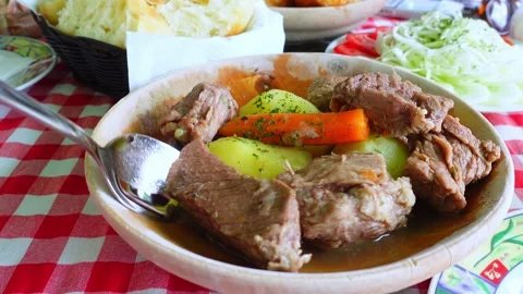 Fork lifting tender beef chunk from stew bowl with potato and carrot on che.. Vídeos de archivo 348624468