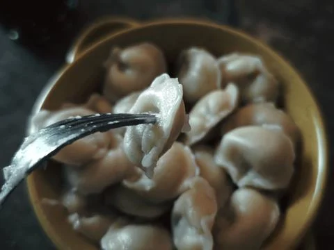Fork picking up a single dumpling from a bowl of dumplings Stock Photos