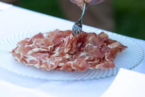 Fork picking sliced prosciutto ham from a plate Stock-Fotos