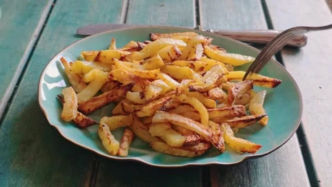 Fork picks up a fried potato piece from a plate of crispy fries. Stock Footage 345166047