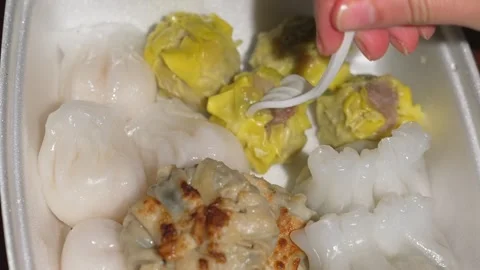 Fork picks siu mai from box of assorted dim sum items Stock Footage 251830022