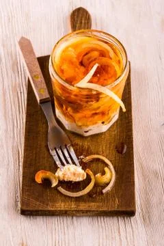 Fork with piece of pickled cheese in front of full jar Stock Photos