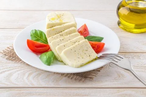 Fork on a plate with rectangular slices of mozzarella, basil and tomato Stock Photos
