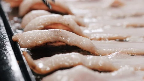 Fork pressed over a slice of uncooked bacon slice on a frying pan Stock-Footage 102569963