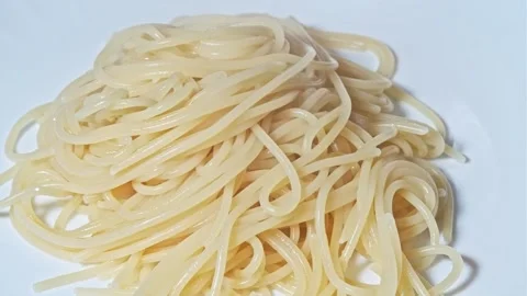 Fork puts hot spaghetti from which steam goes on white plate. Close-up. Stock Footage 247177606
