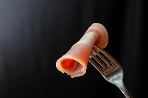 Fork with raw bacon on black background Stock Photos