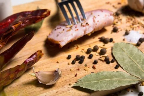 Fork with a slice of bacon on board herbs Stock Photos