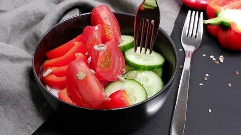 On a fork, a slice of cucumber from a vegetable salad on a black background. Stock Footage 154456743