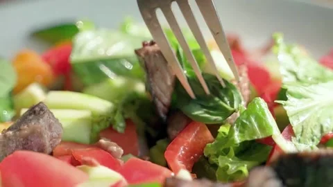The fork slowly stirs fresh salad of greens, bell peppers, cucumbers. Stock Footage 234022015