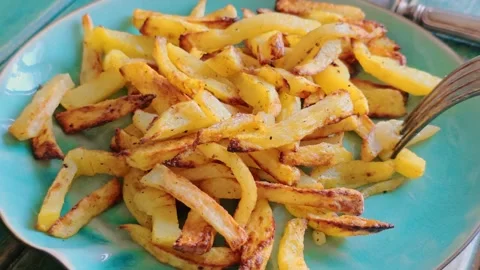 Fork spears several pieces of golden fried potato on a plate. 库存影片 340469652