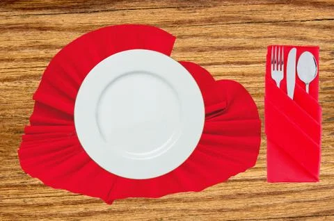 Fork, spoon, knife and white plate on red cloth on wooden table Fotos Stock