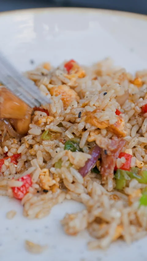 Fork stirring and lifting fried rice with egg and red pepper on a white plate Stock-Footage 347632973