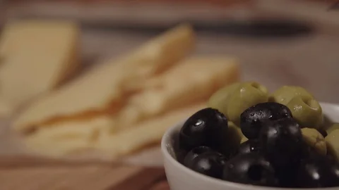 A fork takes an olive from the plate, next on the table is cheese Stock Footage 73919600