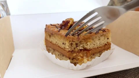 Fork taking bite of layer walnut cake in takeout box Video stock 347671625