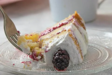 Fork taking a part of a slice of sponge cake filled with whipped cream and be Stock Photos