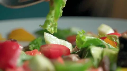 The fork thoroughly mixes a fresh, bright and juicy salad of greens. Video stock 234020732