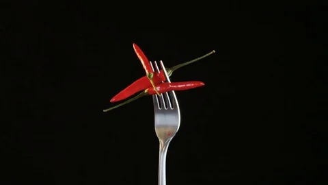 Fork With Three Chili Peppers on Black Background Stock Footage 70535451