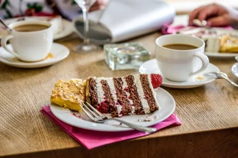Fork on top of a piece of multi layer wedding cake with a cup of coffe on tab Stock Photos