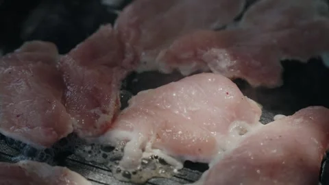 Fork Turning Pale Meat Slices Cooking on a Dark Hot Pan Vídeos de archivo 340595876