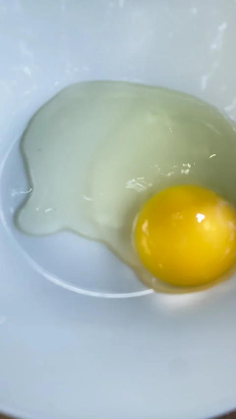 Fork vigorously beating raw yellow eggs in a white bowl preparing ingredients. Vídeos de archivo 341108054