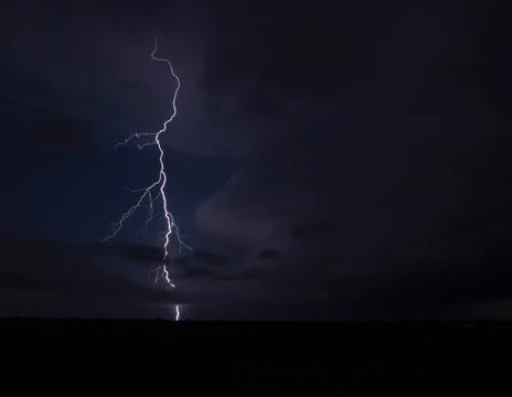 A forking lightning bolt arcs from the anvil of a tornadic thunderstorm in the Stock Photos