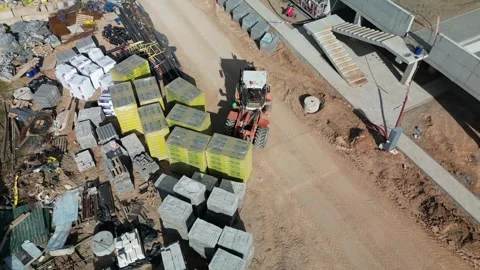 A forklift is actively unloading materials at a construction site. Stock Footage 321948273