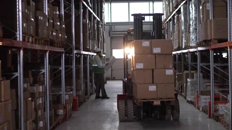Forklift driver lifting boxes up in warehouse Stock Footage 161947399